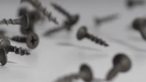 Black iron screws fall onto a white table and crumble bouncing in slow motion. h Stock Footage 131563503