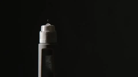Black isolated close-up: Medication squirts from medical injection pen Stock Footage 333475481