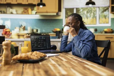 Black IT developer focused on programming tasks at kitchen table 스톡 사진
