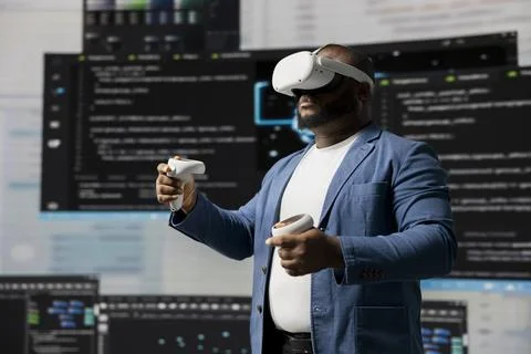 Black IT specialist engineer using VR headset and coding at innovation hub Stock Photos
