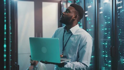 Black IT system administrator working on laptop comnputer running network Stock Footage 119232166