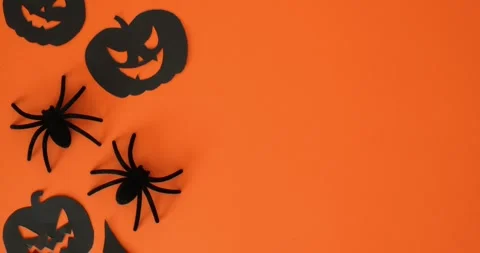 Black jack-o'-lanterns, spiders, and place for text on an orange background Stock Footage 345478827