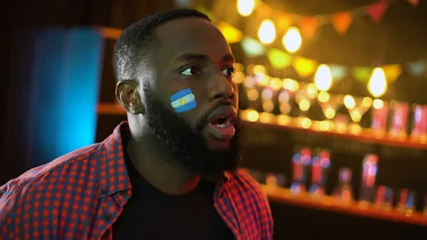 Black joyful soccer supporter with argentinian flag on cheek cheering for team Stock Footage 106914066