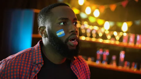Black joyful soccer supporter with argentinian flag on cheek cheering for team Stock Footage 106937538
