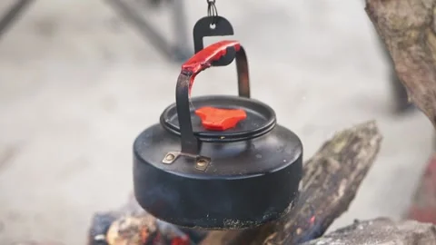 Black kettle heating over outdoor bonfire hanging from metal hook in natura.. Stock Footage 344338115