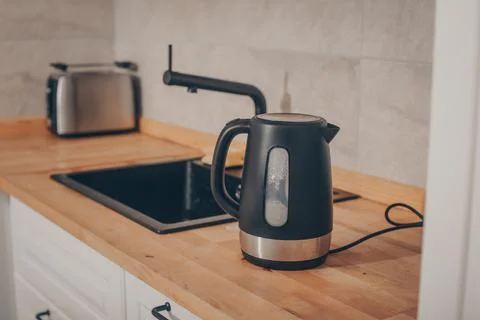 A black kettle is on the kitchen table. Foto stock