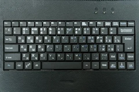 Black keyboard layout with Cyrillic and Latin letters on dark surface Stock Photos
