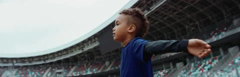 Black kid boy spreading hands on a stadium, dreaming of becoming famous player Stock Footage 135170289