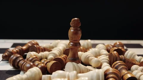 Black king standing among fallen chess pieces, concept of victory and dominance Stock Footage 329584367