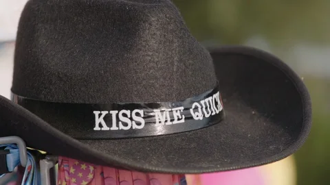 Black kiss me quick hat for sale in the sun at the seaside Stock Footage 129692324