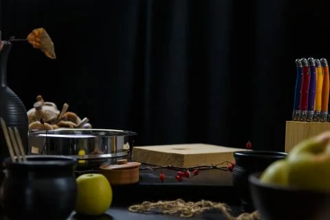 Black kitchen table with set of knives, some dishes, apples and mushrooms Stock Photos