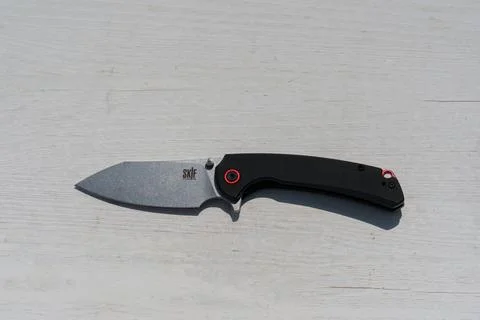 A black knife with a red button on the handle Stock Photos