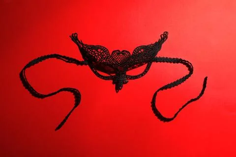 Black lace mask on red background, top view. Accessory for sexual role play Stock Photos