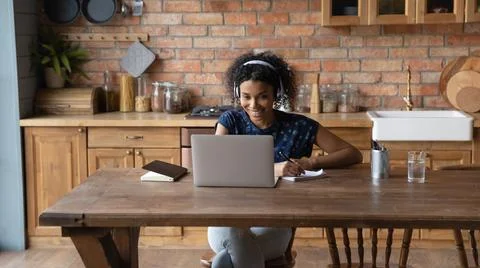 Black lady in headphones watch webinar on laptop taking notes Stock Photos