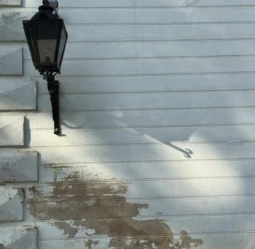 Black Lantern on Sunlit Façade with Peeling Plaster and Shadow Stock Photos