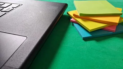 Black laptop computer beside a stack of colorful sticky notes Stock Photos