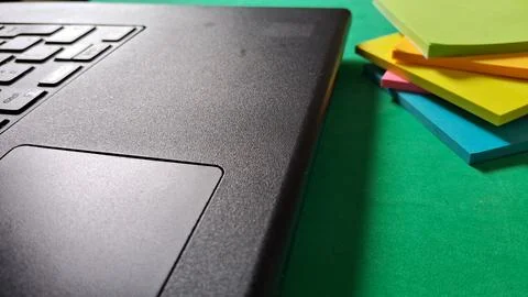 Black laptop computer sitting on a bright green workspace surface area Stock Photos