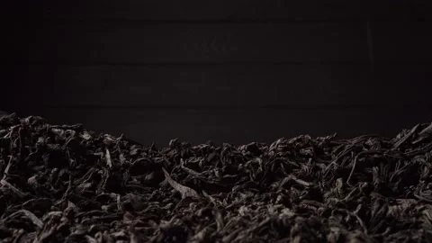 Black large-leaf tea is poured into a pile. Close-up, side view. Stock Footage 237875088