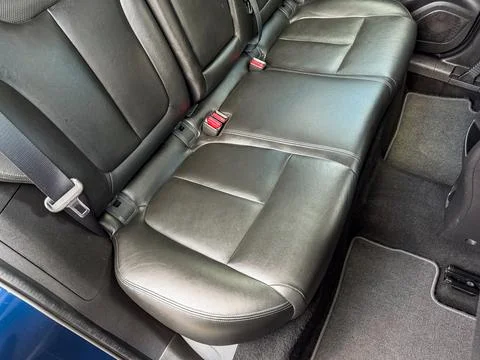 The black leather back seat is empty and well-maintained. The seat has two se Stock Photos