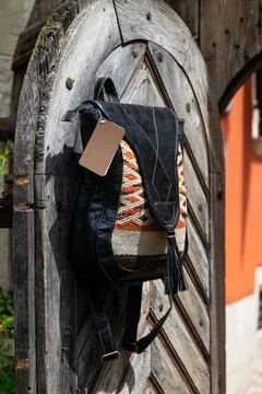 Black leather backpack with a pattern on the wooden door Stock Photos