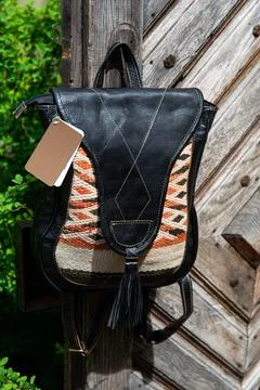 Black leather backpack with a pattern on the wooden door Stock Photos