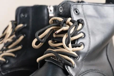Black leather boots with beige laces on light background Stock Photos