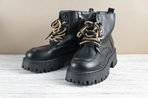Black leather boots with beige laces on light background Stock Photos