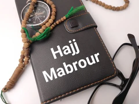 A black leather folder reading Hajj Mabrour is placed beside a compass, gla.. Stock Photos