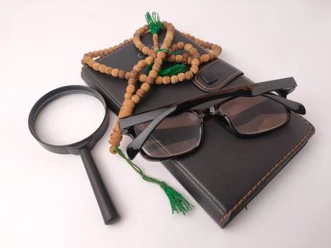 A black leather planner topped with reading glasses, a magnifying glass, an.. Stock Photos