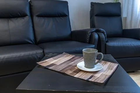 A black leather sofa with a lounge function in the living room of the apart.. Stock Photos