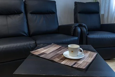 A black leather sofa with a lounge function in the living room of the apart.. Stock Photos