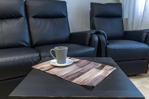 A black leather sofa with a lounge function in the living room of the apart.. Stock Photos
