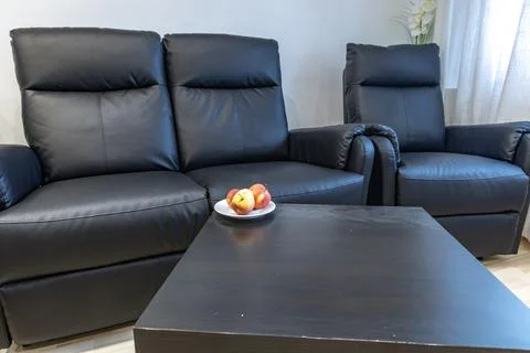 A black leather sofa with a lounge function in the living room of the apart.. Stock Photos