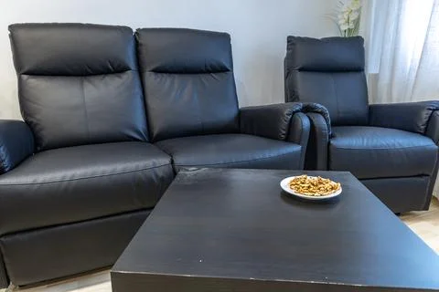 A black leather sofa with a lounge function in the living room of the apart.. Stock Photos