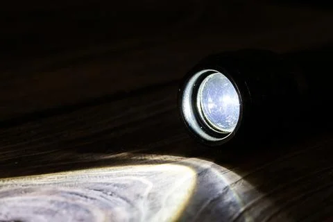 Black led operational flashlight on rough wooden surface - closeup with Stock Photos