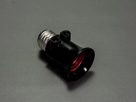 A black light socket with a silver metal base rests angled on a textured gr.. Stock Photos