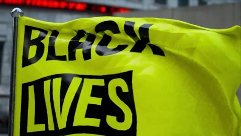 A Black lives matter text CGI realistic yellow flag in city downtown close up Stock Footage 155305469
