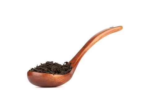 Black loose leaf tea on an elegant wooden spoon over a white background. Stock Photos