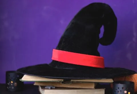 Black magic hat on the open book on purple background Stock Photos