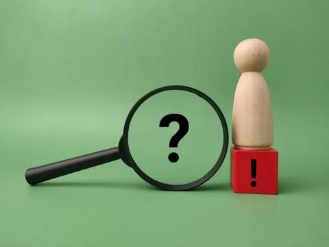 A black magnifying glass frames a question mark next to a wooden figure sta.. Stock Photos