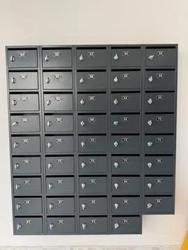 Black mailboxes arranged in a grid pattern on a beige wall suitable as a ba.. Stock Photos