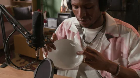 Black Male Audio Engineer Recording Plate Scraping through Mic in Home Studio Stock Footage 335396133