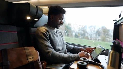 Black male commuter working on tablet computer traveling by train Stock Footage 323069861