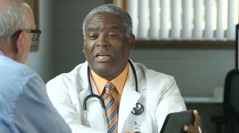Black male doctor using an ipad/tablet with a senior male patient Stock Footage