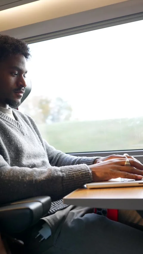 Black male freelancer working remotely on laptop during business train trip Stock Footage 323069939