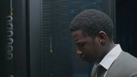 Black Male IT Administrator Analyzing Work of Mainframe in Data Center Stock Footage 303555719