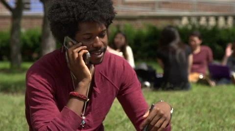 A Black male student talks on cell phone, outside. Stock Footage 44117151