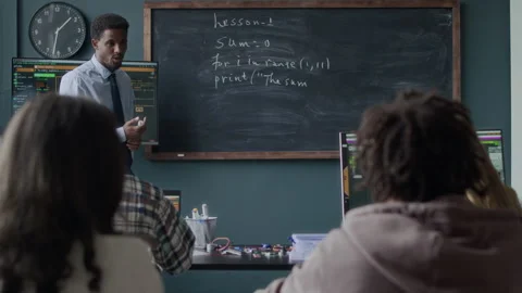 Black Male Teacher Giving Programming Lesson to Teenage Students in Classroom Stock Footage 284428741