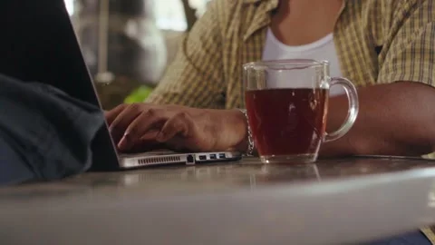 Black male typing on laptop computer at an outdoor cafe Stock Footage 344760933
