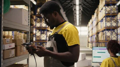 Black male worker using scanner checking airway bill numbers in inventory Stock Photos